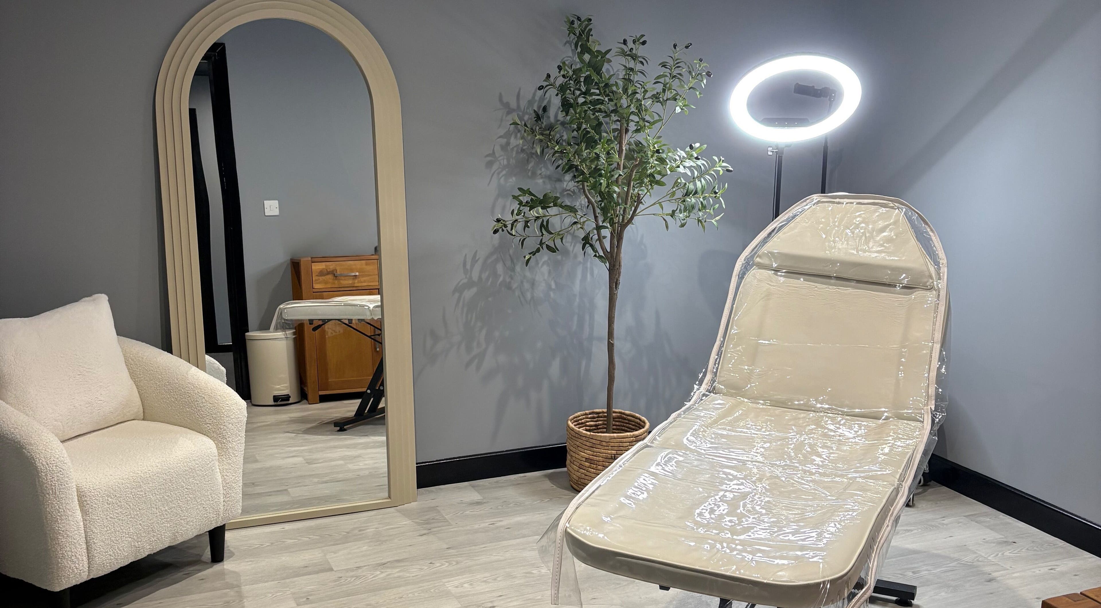 Elegant treatment room at All About Aesthetics, Fareham, England, GB with chair, mirror, and plant.