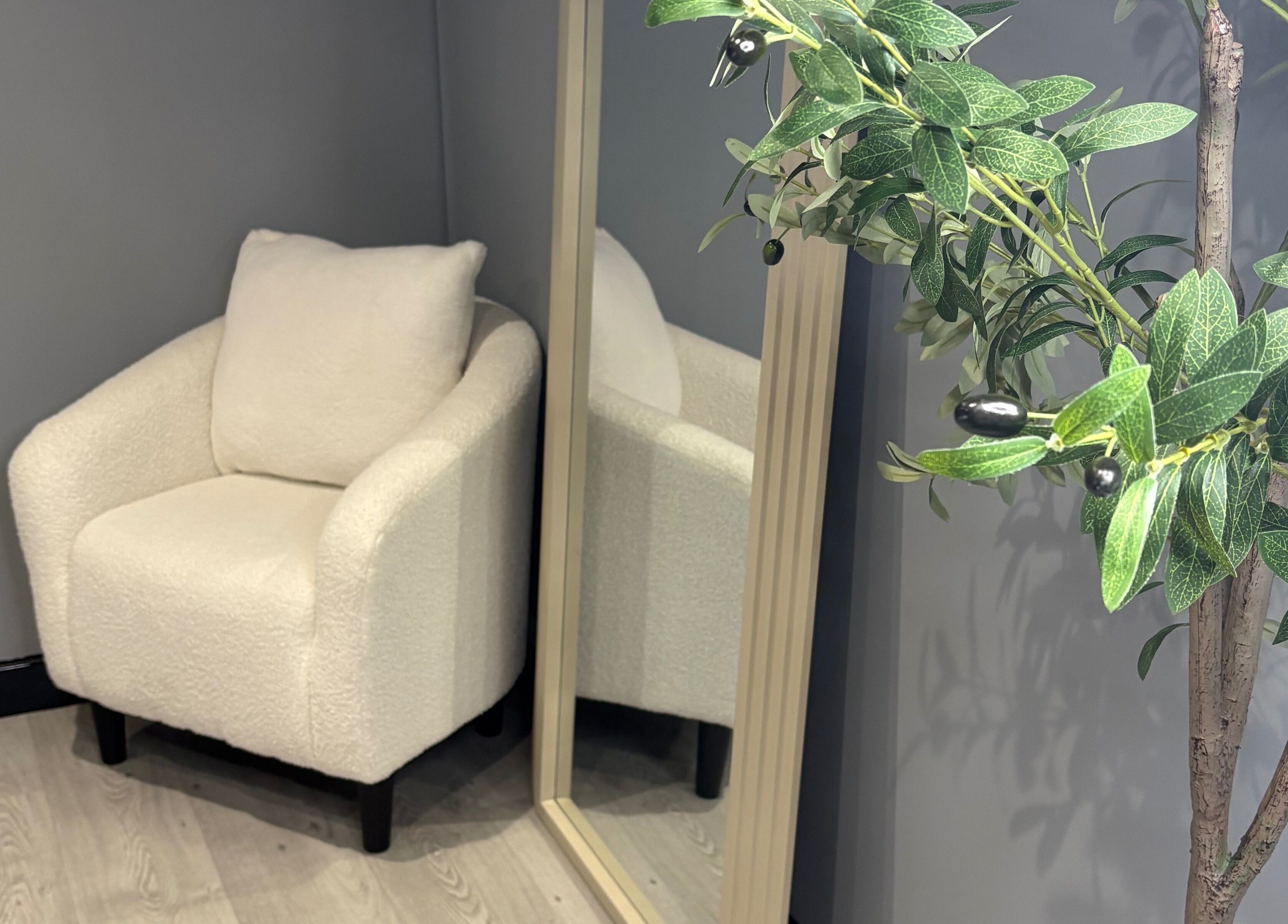 Elegant corner at All About Aesthetics, Fareham, England, GB with white chair, mirror, and plant.