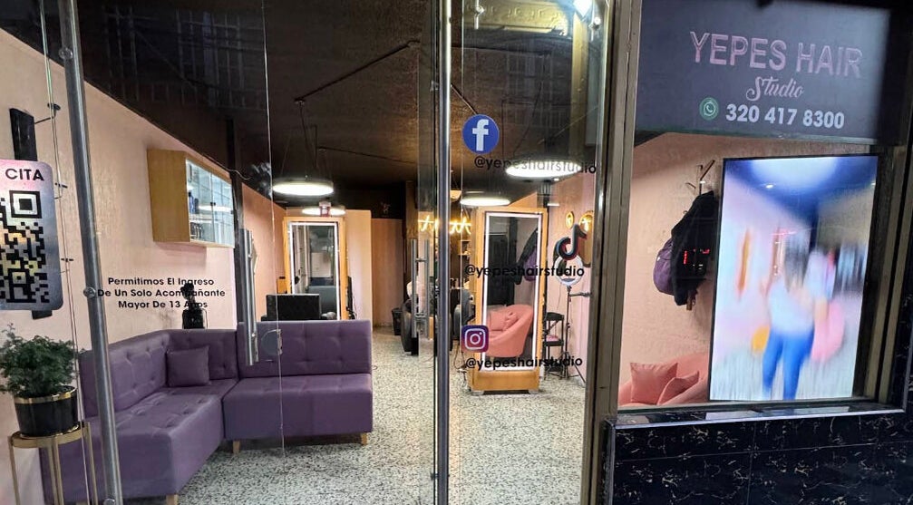 Entrada a Yepes Hair Studio en Soacha, Cundinamarca, CO, decorada con sofás lila y espejos elegantes.
