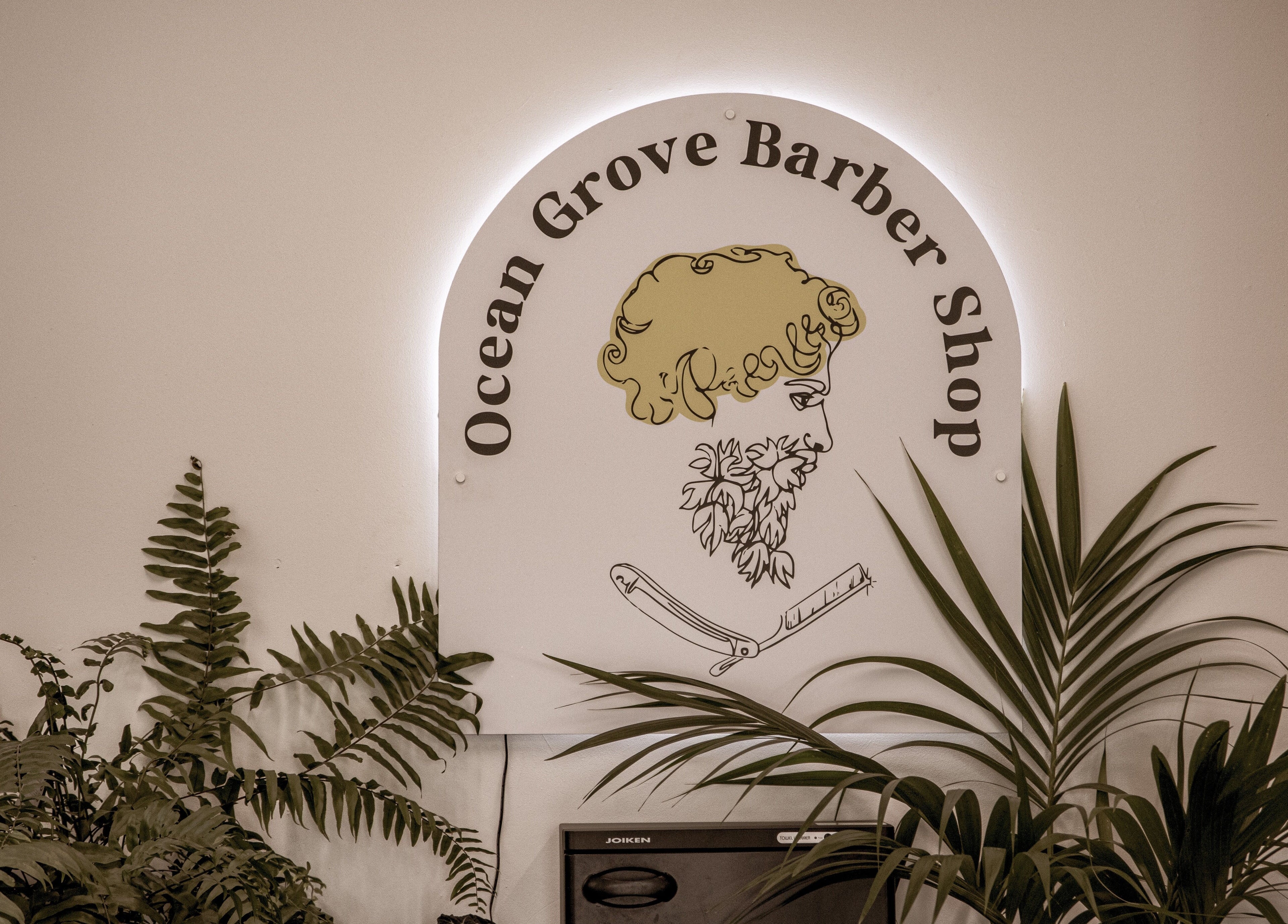Ocean Grove Barbershop logo surrounded by plants, showcasing modern style in Ocean Grove, VIC, AU.