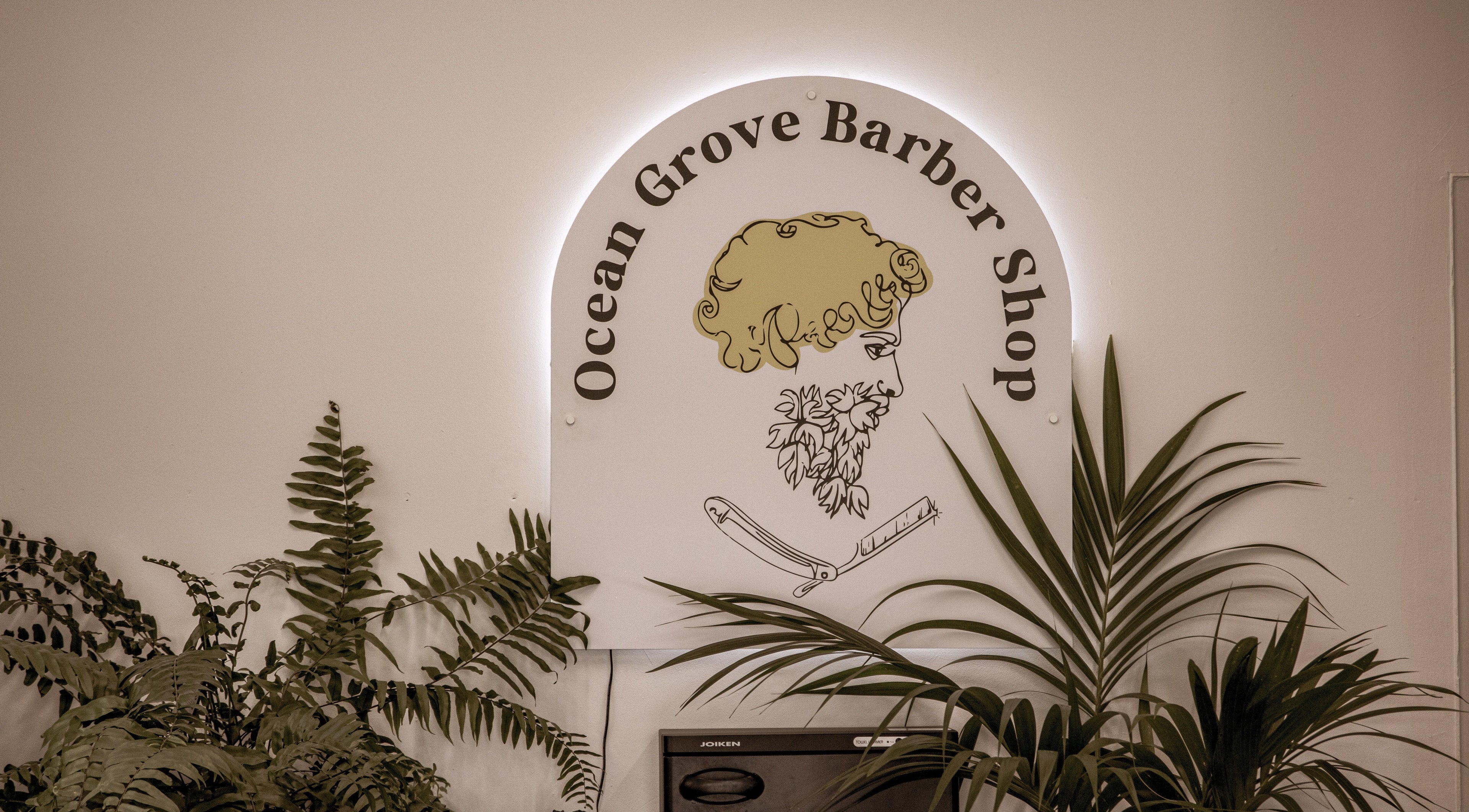 Ocean Grove Barbershop logo surrounded by plants, showcasing modern style in Ocean Grove, VIC, AU.