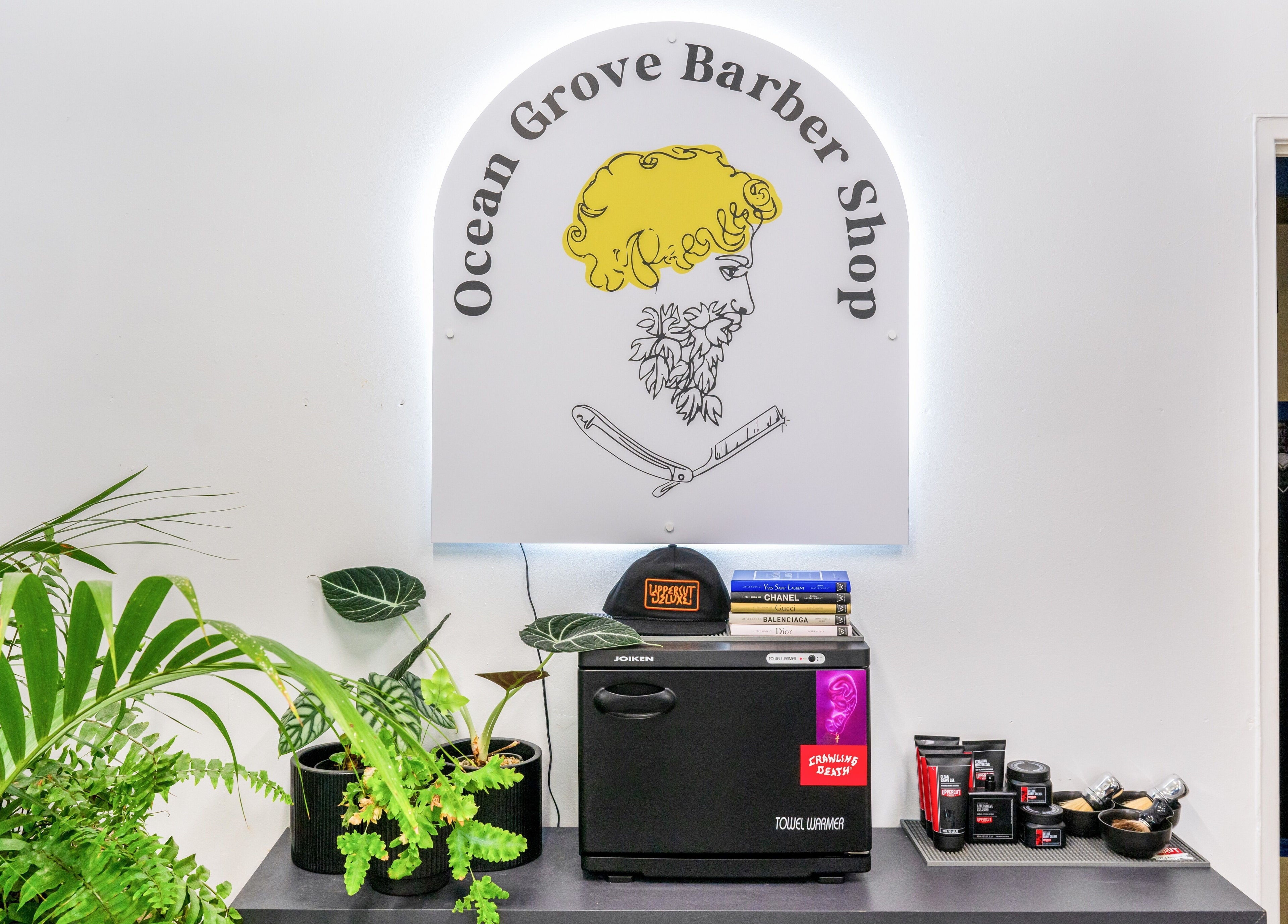 Interior of Ocean Grove Barbershop in Ocean Grove, VIC, AU featuring a stylish greenery display and grooming products.