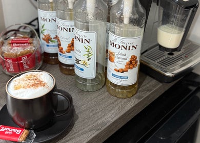 Coffee station at Ivor Hairdressing, Stoke-on-Trent, England, GB, featuring syrups, Biscoff cookies, and espresso machine.