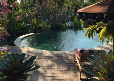 Peaceful poolside with lush greenery at Alam Wellness Bali in Denpasar, Bali, ID, offering serene relaxation.