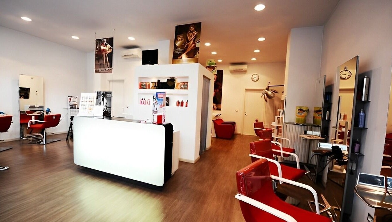 Interno moderno del salone Spazio uomo donna a Brescia, Lombardia, IT, con poltrone rosse e arredi eleganti.