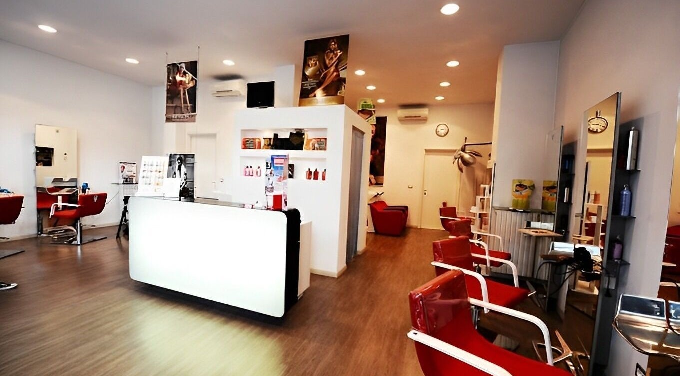 Interno moderno del salone Spazio uomo donna a Brescia, Lombardia, IT, con poltrone rosse e arredi eleganti.