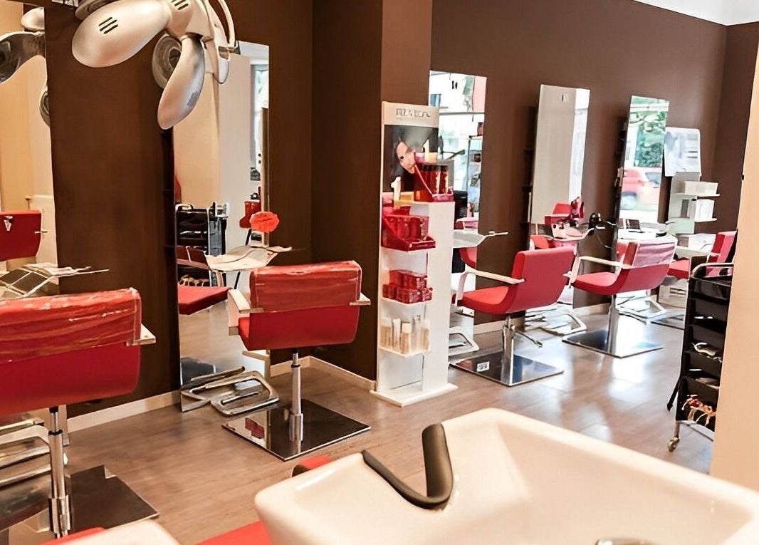 Interno del salone Spazio uomo donna a Brescia, Lombardia, IT con sedie rosse moderne e specchi.