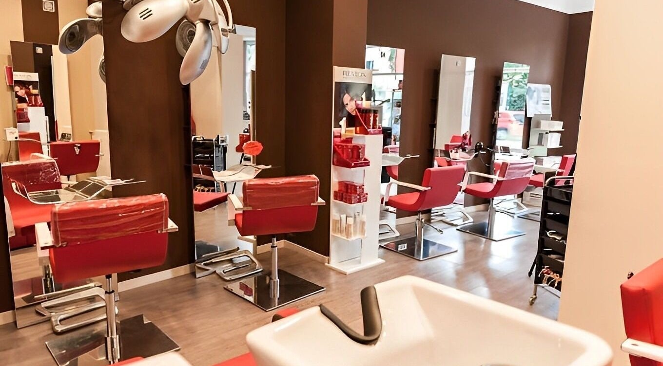 Interno del salone Spazio uomo donna a Brescia, Lombardia, IT con sedie rosse moderne e specchi.