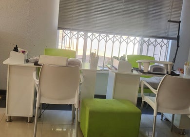 Manicure stations at Sparkle Nail Studio in Roodepoort, Gauteng, ZA, featuring modern white chairs and green stools.