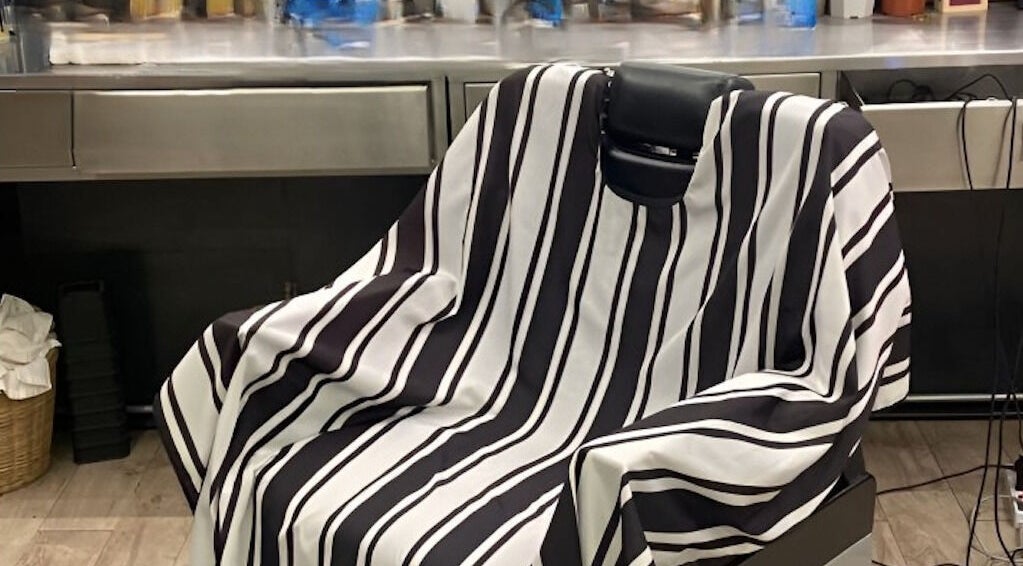 Barber chair with a striped cape at Bmore Barbers Bkk, Krung Thep Maha Nakhon, TH.