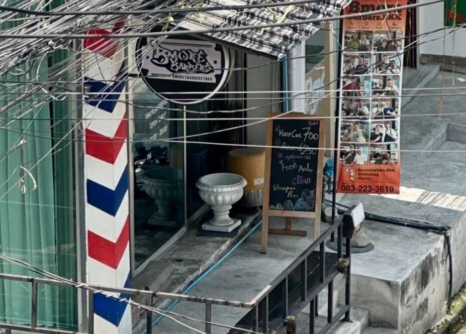 Entrance of Bmore Barbers Bkk in Krung Thep Maha Nakhon, decorated with a classic barber pole and signage.
