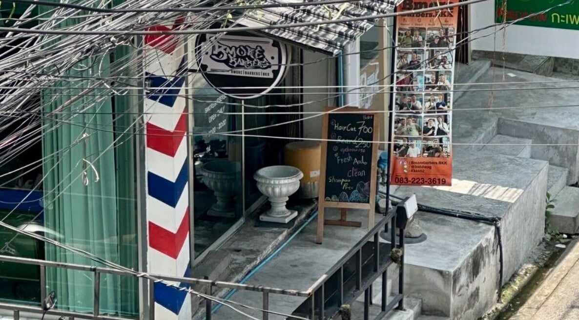 Entrance of Bmore Barbers Bkk in Krung Thep Maha Nakhon, decorated with a classic barber pole and signage.