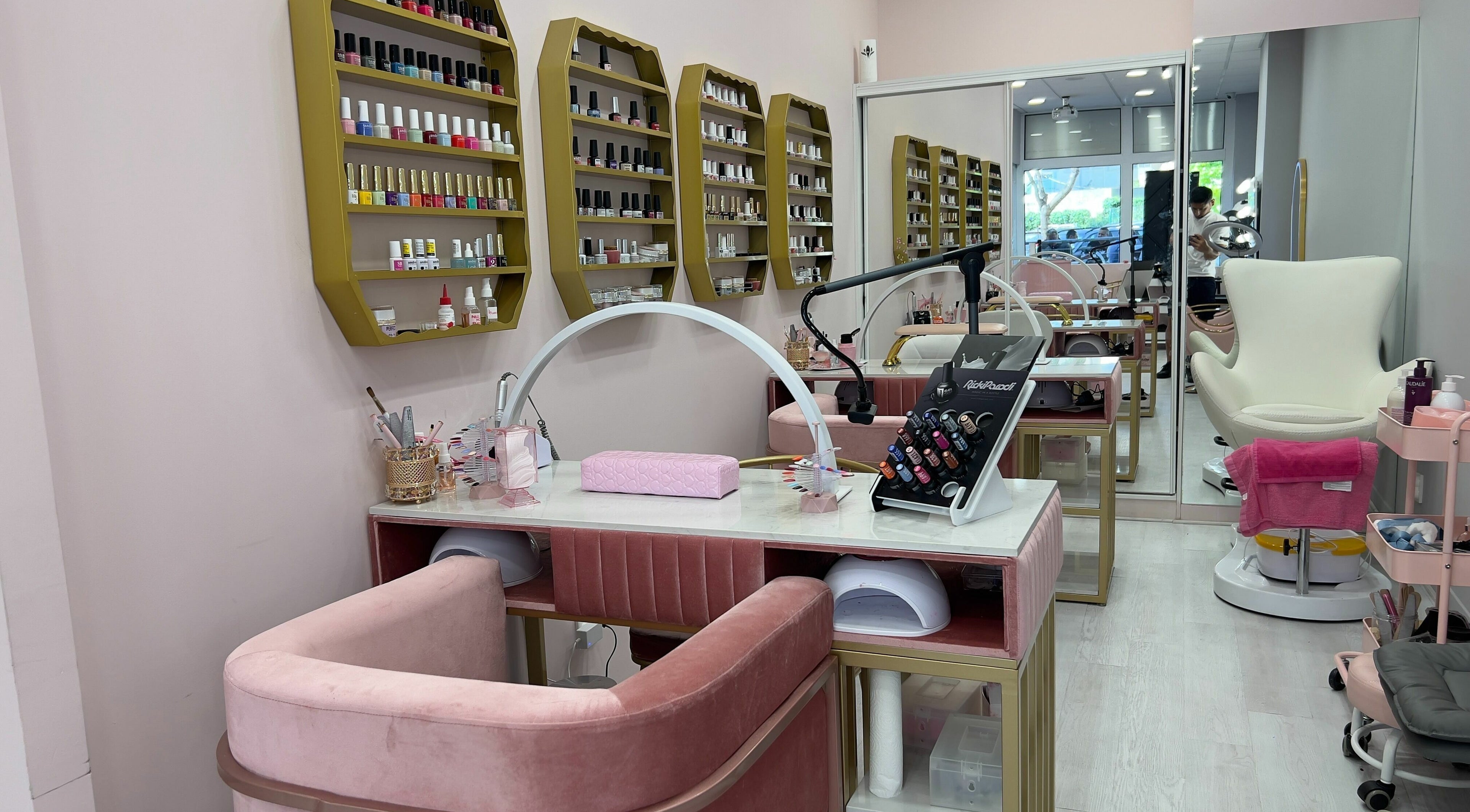 Elegant nail salon at Curls and Glow, Lisboa, Lisboa, PT with plush seating and colorful nail polish display.