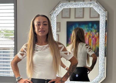 Stylish woman at Permanent Aesthetics Studio, Burton Upon Trent, England, GB, posing by a decorative mirror.