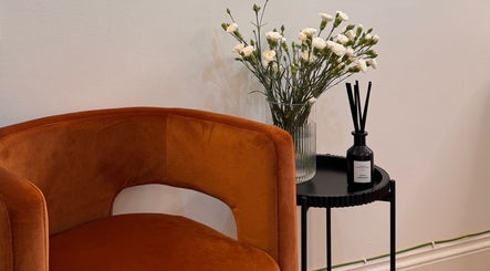 A cozy brown chair with flowers and diffuser at Ola’s Studio26, Cheltenham, England, GB.
