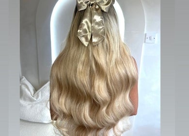 Woman with long, wavy blonde hair and a golden bow at Slae Salon, North Shields, England, GB.