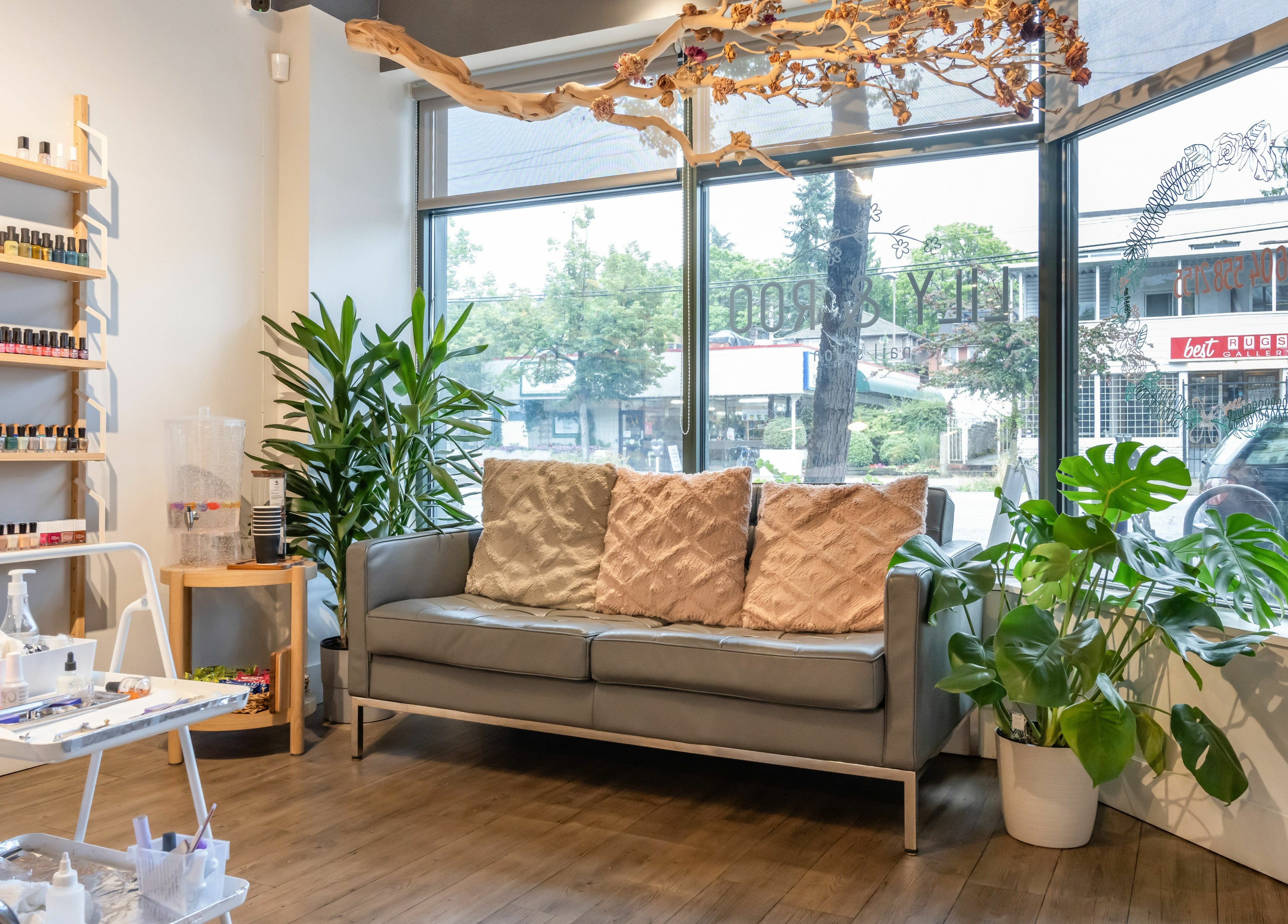 Chic waiting area at Lily & Roo Nail Salon in Vancouver, British Columbia, CA with a comfy sofa and plant decor.