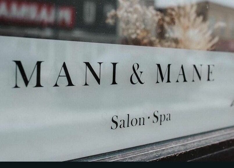 Mani & Mane salon window sign at Lucknow, Ontario, CA offering beauty and wellness services.