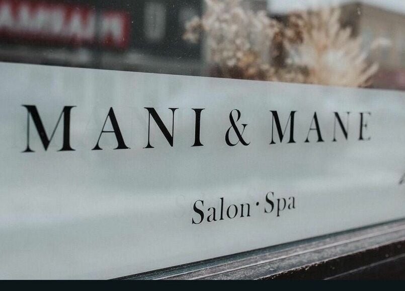 Mani & Mane salon window sign at Lucknow, Ontario, CA offering beauty and wellness services.