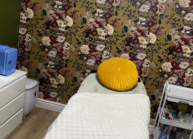 Cozy treatment room at Ella Bella beauty in Leek, England, GB with floral wallpaper and yellow cushion.