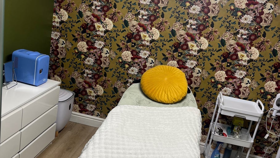 Tranquil treatment room at Ella Bella Beauty, Leek, England, GB with vibrant floral wallpaper and cozy bed.