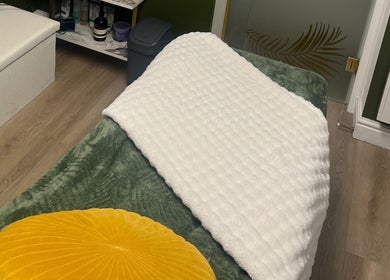 Relaxing treatment room at Ella Bella Beauty, Leek, England, GB with a green blanket and yellow cushion.