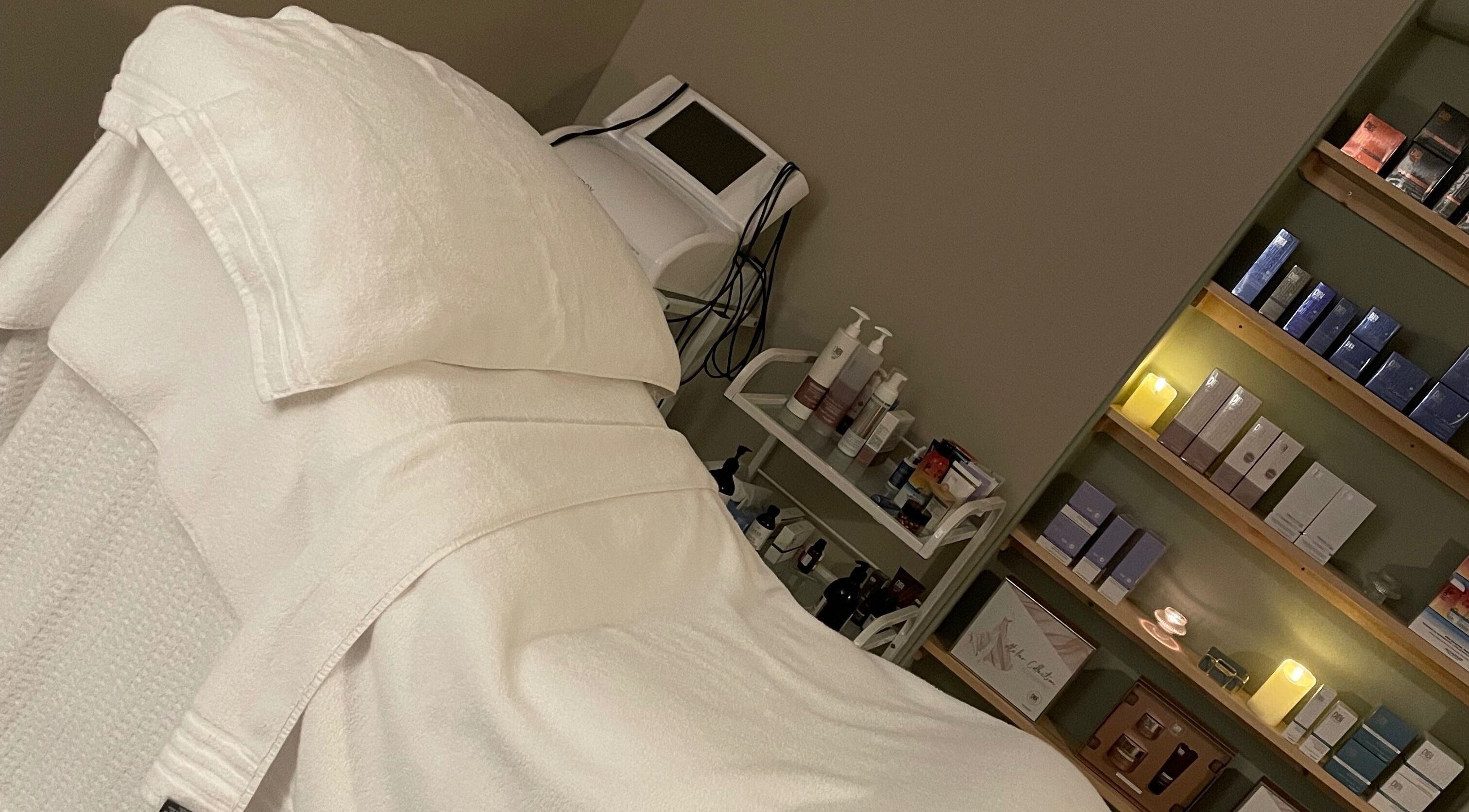 Cozy treatment room at The Skin Corner by Amy in Shaftesbury, England, GB, showcasing plush bedding and skincare products.