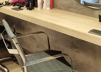 Estación de trabajo moderna en Natalia Hairstylist en San Juan, San Juan, AR, con sillas y productos de belleza.