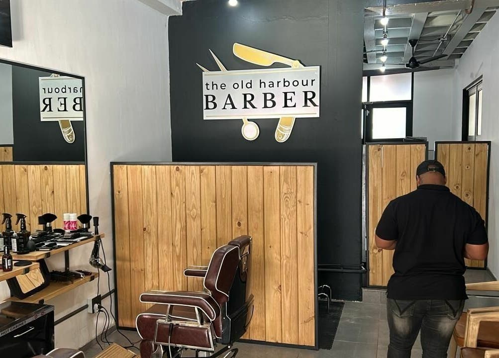 Interior view of The Old Harbour Barber, Hermanus, Western Cape, ZA, featuring stylish seating and wood decor.