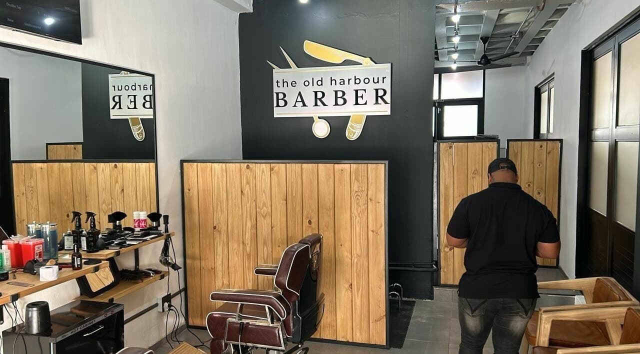 Interior view of The Old Harbour Barber, Hermanus, Western Cape, ZA, featuring stylish seating and wood decor.