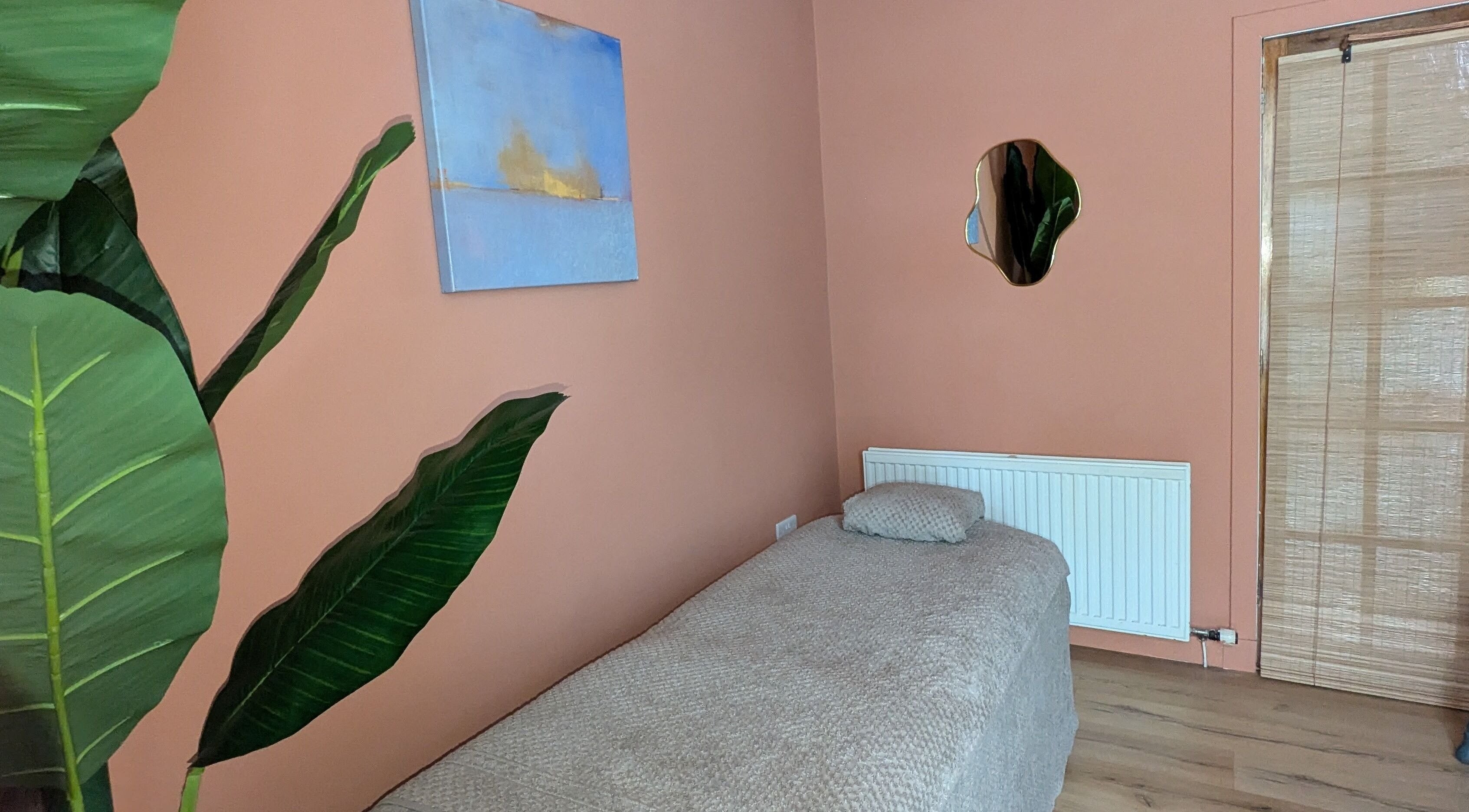 Cozy treatment room at Remedy Room West, Glasgow, Scotland featuring calming decor and a massage bed.