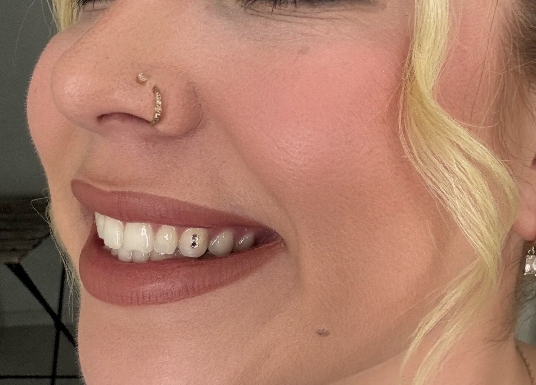 A close-up of a woman with nose ring smiling with gem-decorated teeth at Be Glamorous Studio, Kallangur, Queensland, AU.