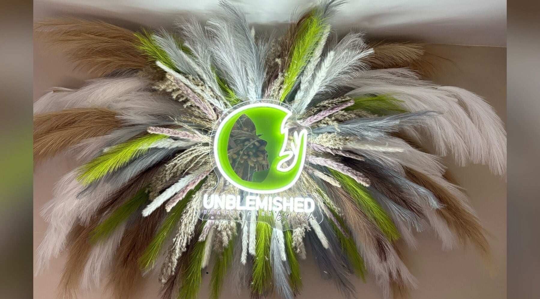 Neon logo of Unblemished by Tish (FLORIDA) with decorative feathers in Davie, Florida, US.