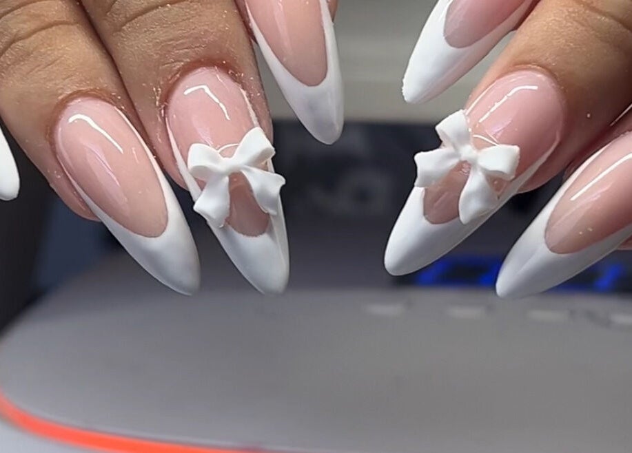 Elegant french-tipped nails with 3D bows at Demi.DidThem, Port St. Lucie, Florida, US.