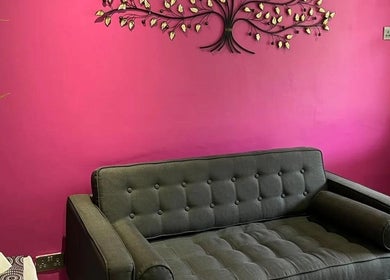 Cozy grey sofa against bright pink wall with art at Mist Beauty, Southend-on-Sea, England, GB.