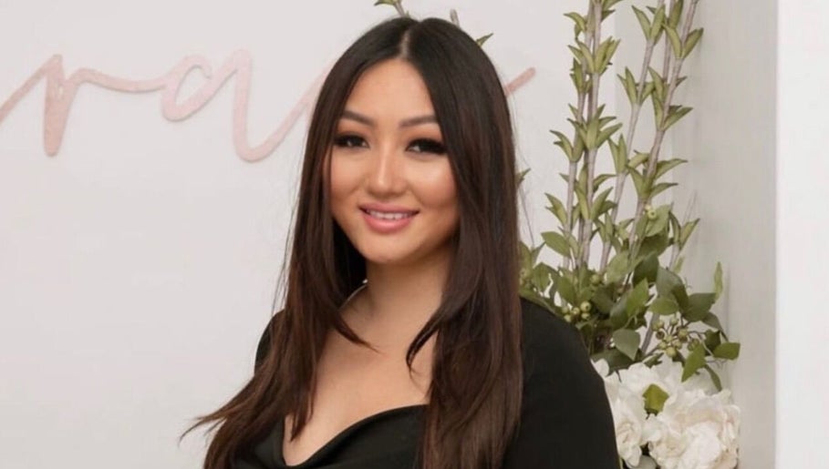 Staff member at Grace Brows & Beauty, Penrith, New South Wales, AU, with welcoming smile and floral decor.