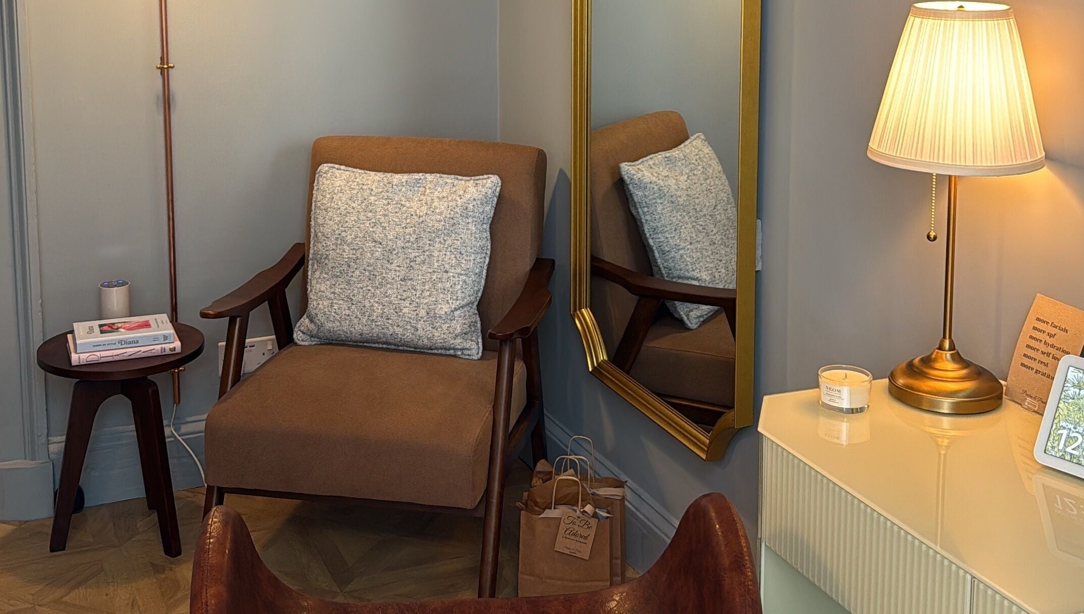 Elegant seating area at Peaches & Pearls Studio, Dundee, Scotland, GB, featuring a brown armchair and gold lamp.