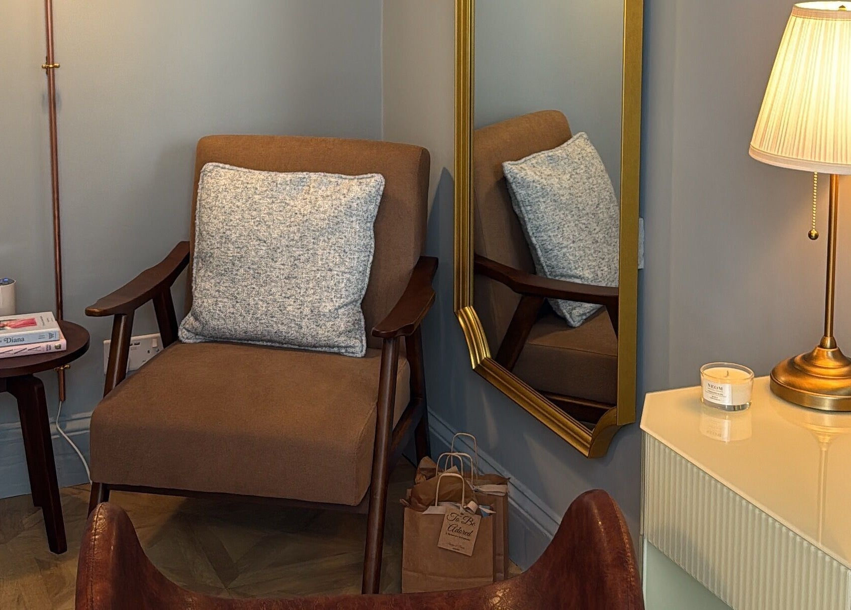 Elegant seating area at Peaches & Pearls Studio, Dundee, Scotland, GB, featuring a brown armchair and gold lamp.