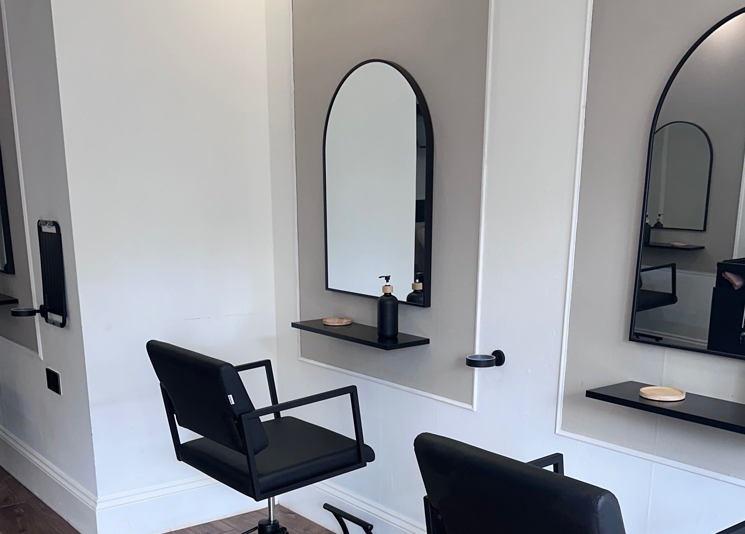 Modern styling stations at Lottana Hair Salon in Greenfield, England, GB, featuring sleek mirrors and chairs.