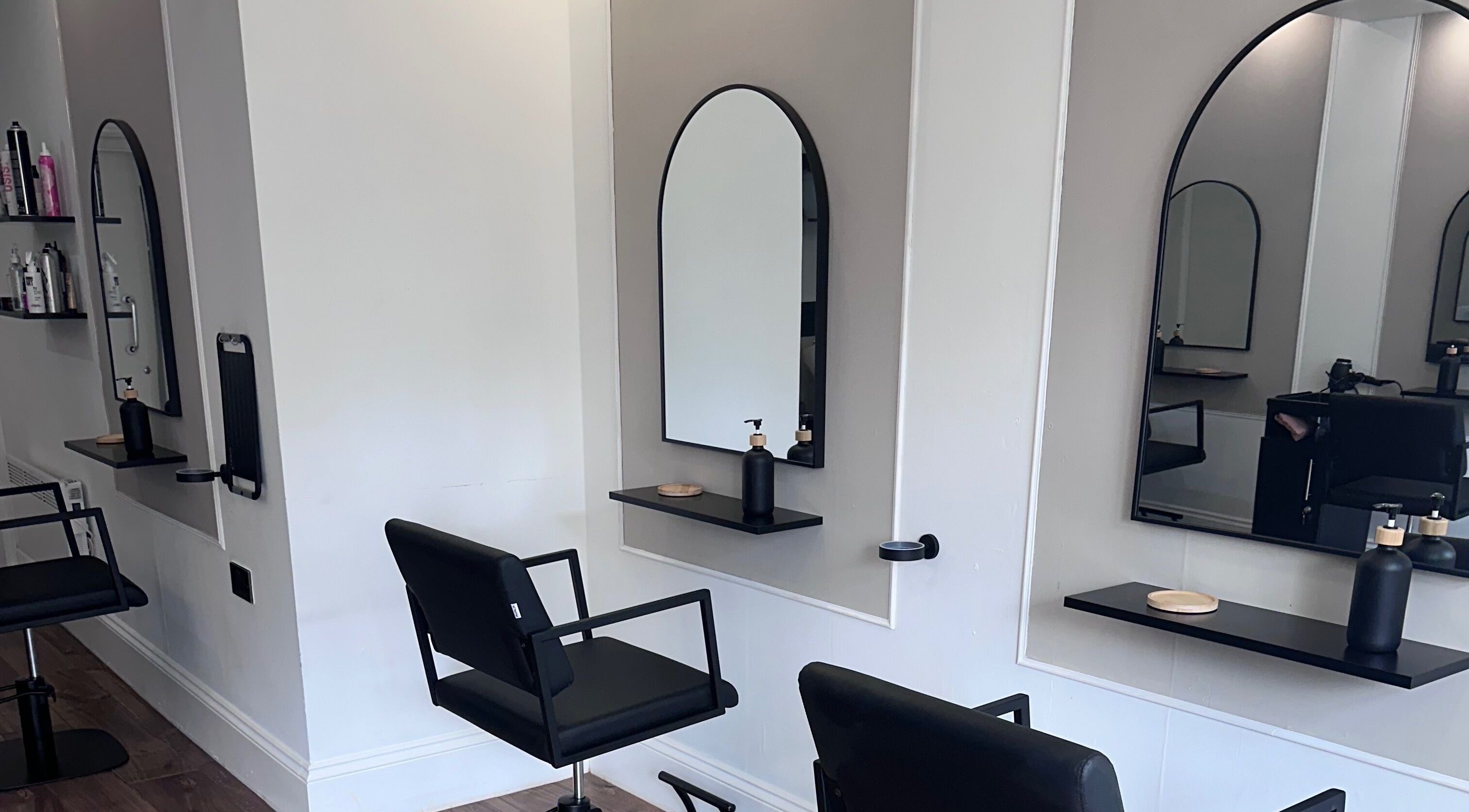 Modern styling stations at Lottana Hair Salon in Greenfield, England, GB, featuring sleek mirrors and chairs.