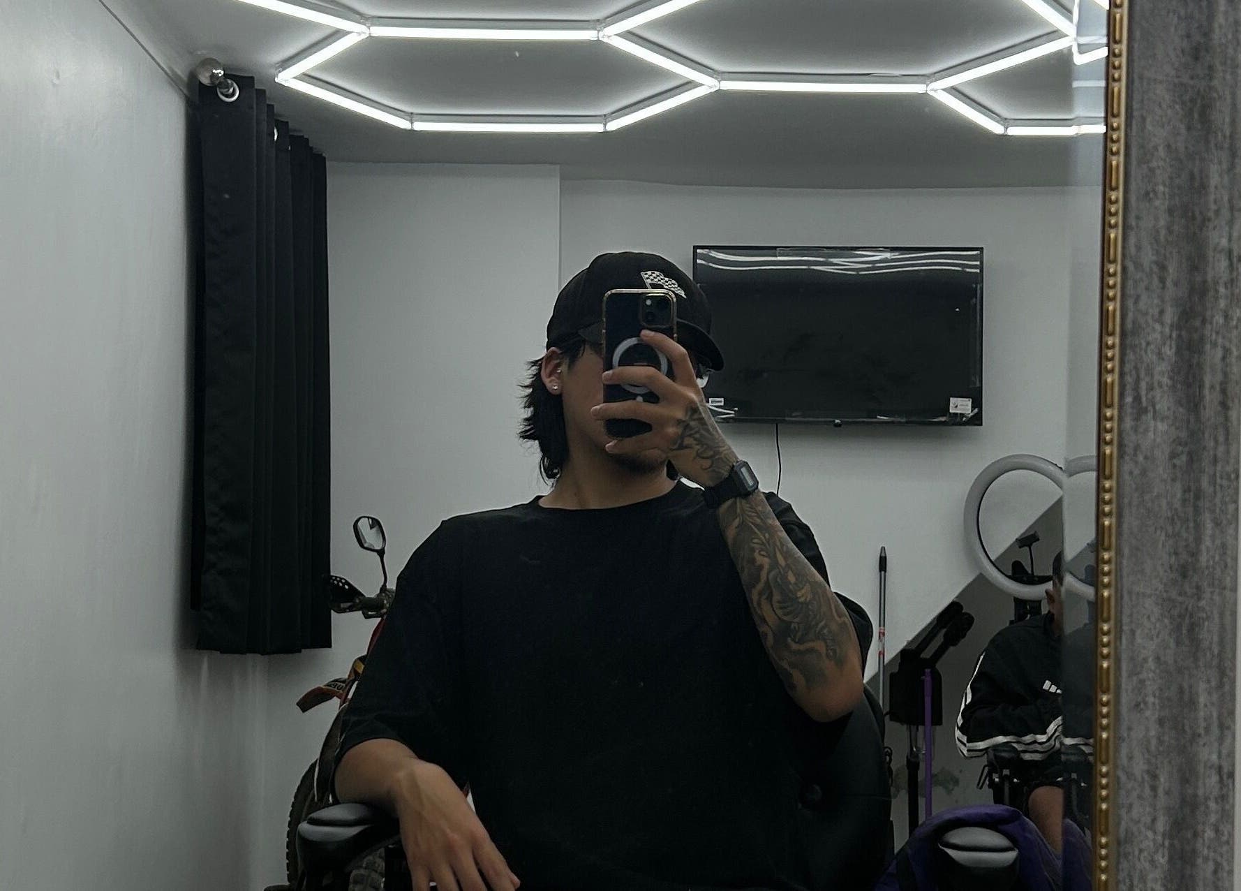 Interior moderno de Ryuk Barber en Chimbote, Áncash, PE, reflejado en un gran espejo.