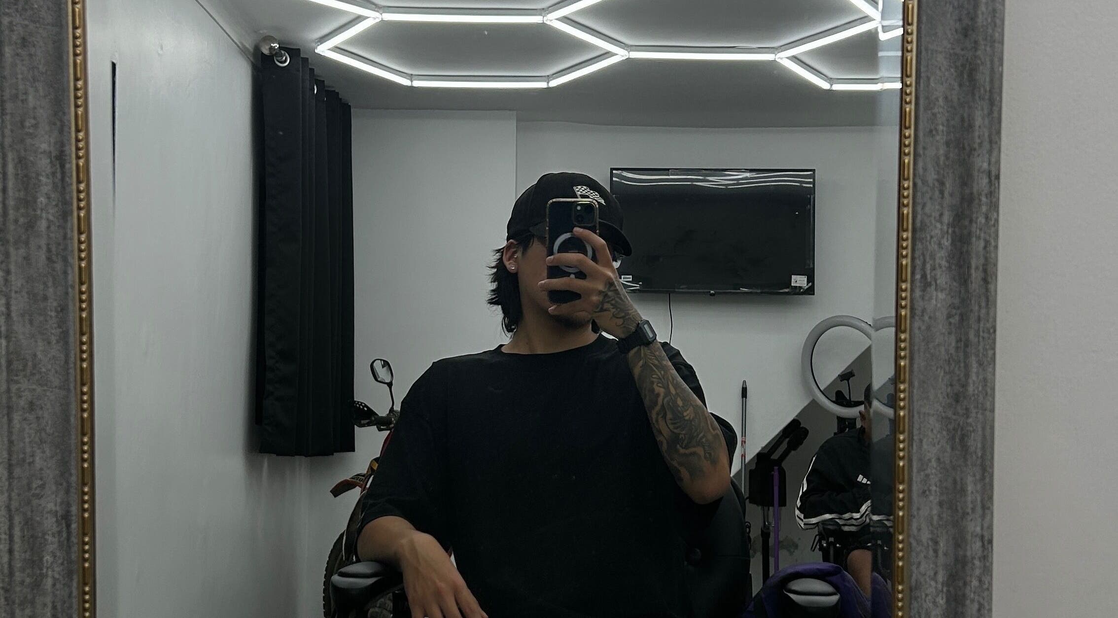 Interior moderno de Ryuk Barber en Chimbote, Áncash, PE, reflejado en un gran espejo.