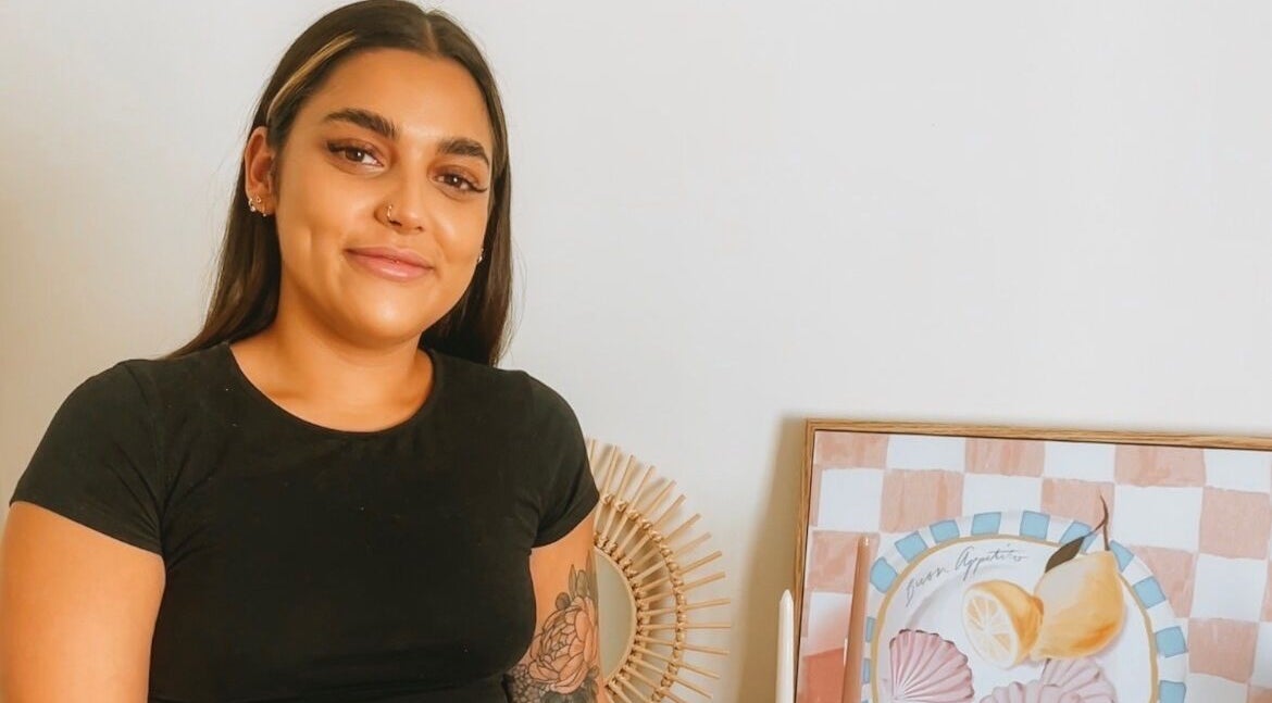 Person smiling beside art decor at LashX Beauty in Mount Hawthorn, Western Australia, AU.