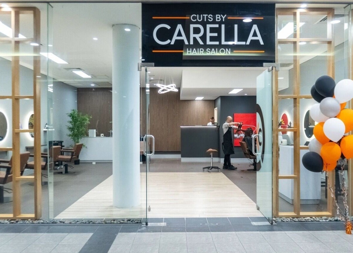 Cuts By Carella entrance with glass doors in Cairns City, Queensland, AU. Elegant salon interior visible.