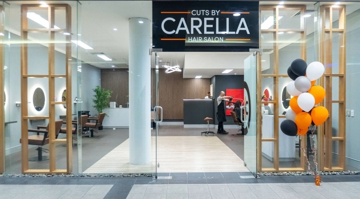 Cuts By Carella entrance with glass doors in Cairns City, Queensland, AU. Elegant salon interior visible.