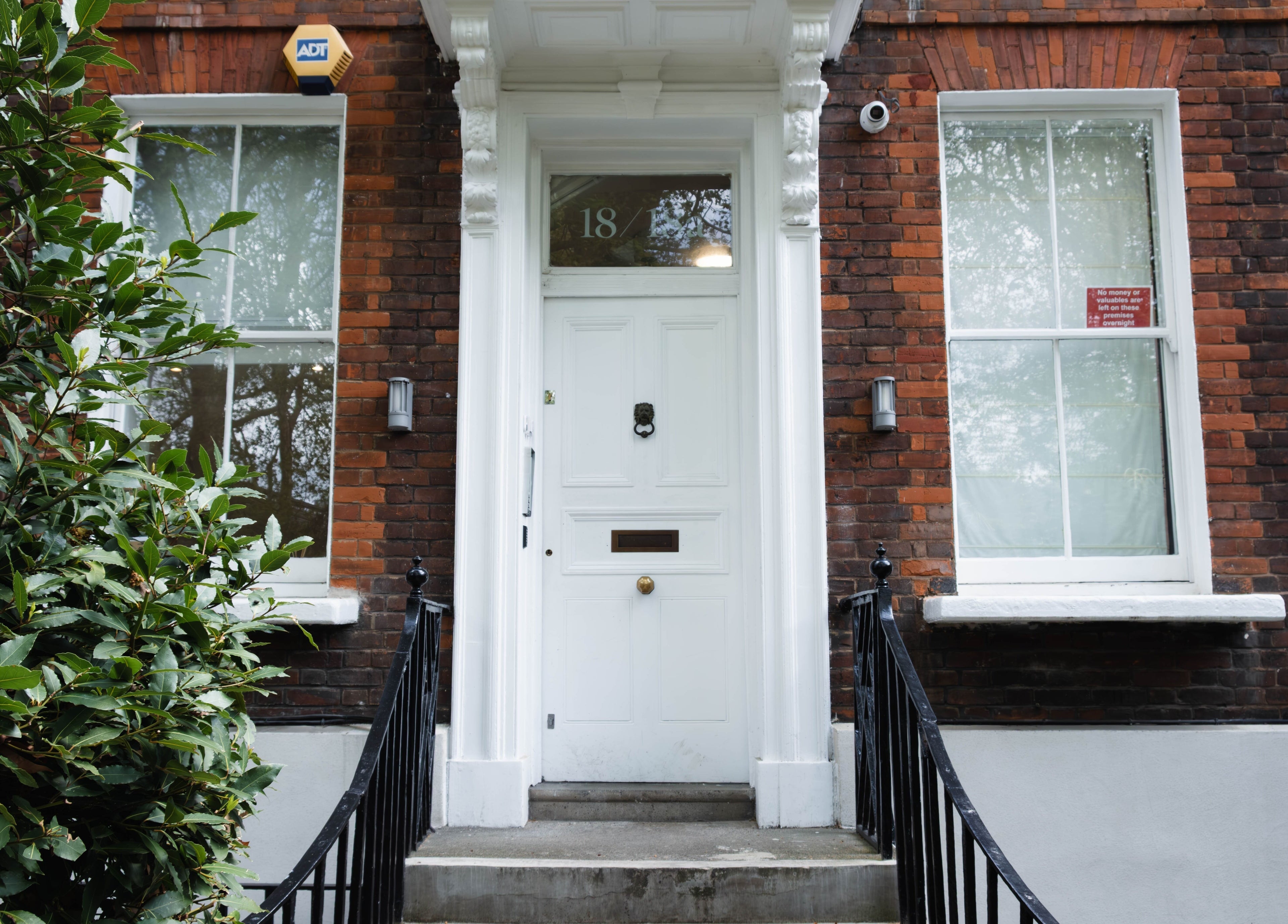 Classic brick facade of Nayii Atelier奈野 at London, England, GB. Welcoming white door with greenery.