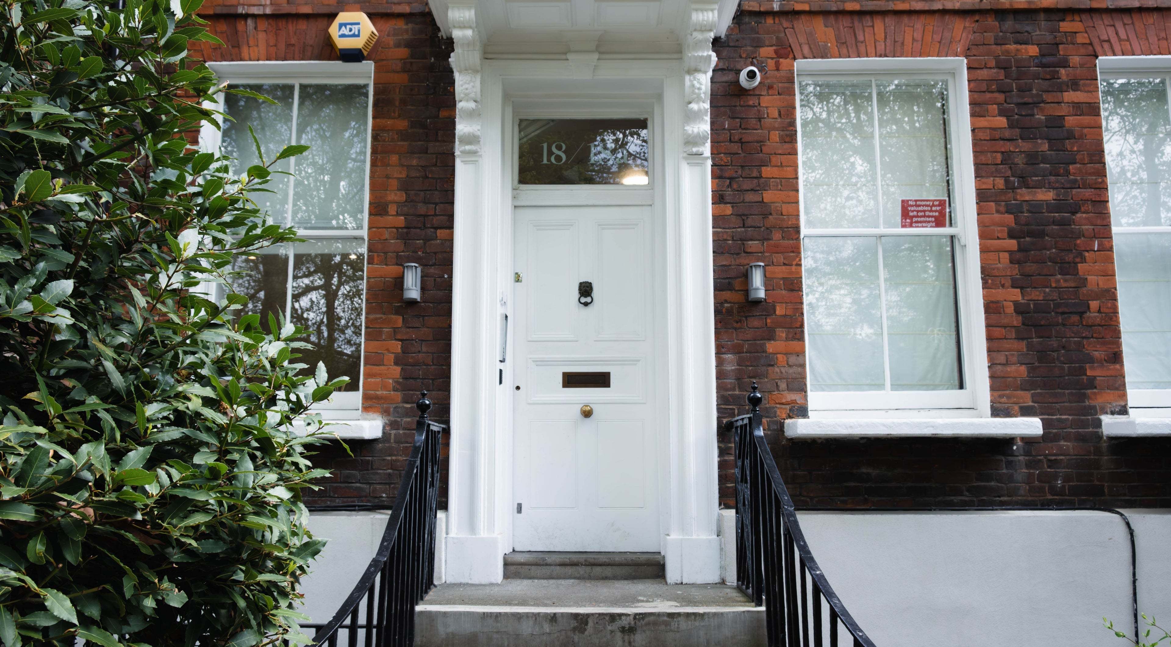 Classic brick facade of Nayii Atelier奈野 at London, England, GB. Welcoming white door with greenery.