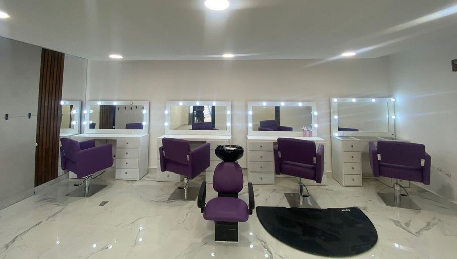 Área de peluquería moderna en Lesslie Beauty, Monterrey, Nuevo León, MX con sillones morados y espejos iluminados.