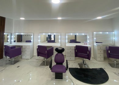 Área de peluquería moderna en Lesslie Beauty, Monterrey, Nuevo León, MX con sillones morados y espejos iluminados.