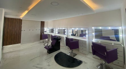 Sala de belleza elegante en Lesslie Beauty, Monterrey, Nuevo León, MX, con sillas moradas y espejos iluminados.